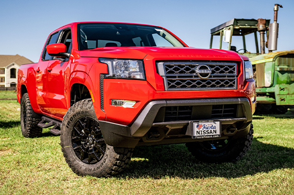 3/4 view of a red Nissan Truck outside in a field