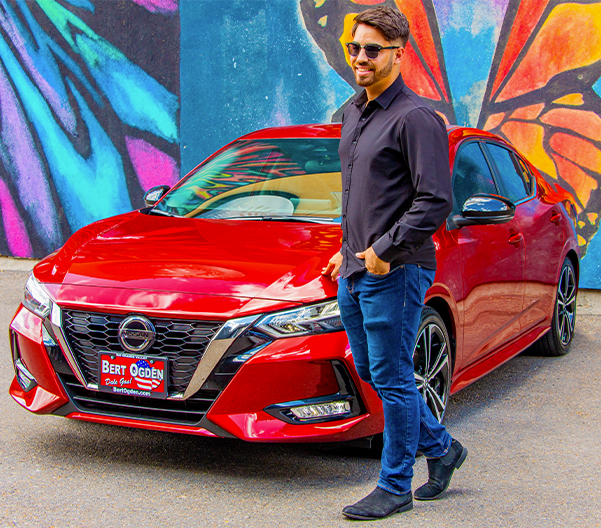 stylish man standing in front of his used nissan sentra