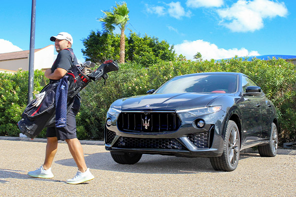 man walking away from a new maserati parked in front of palm trees