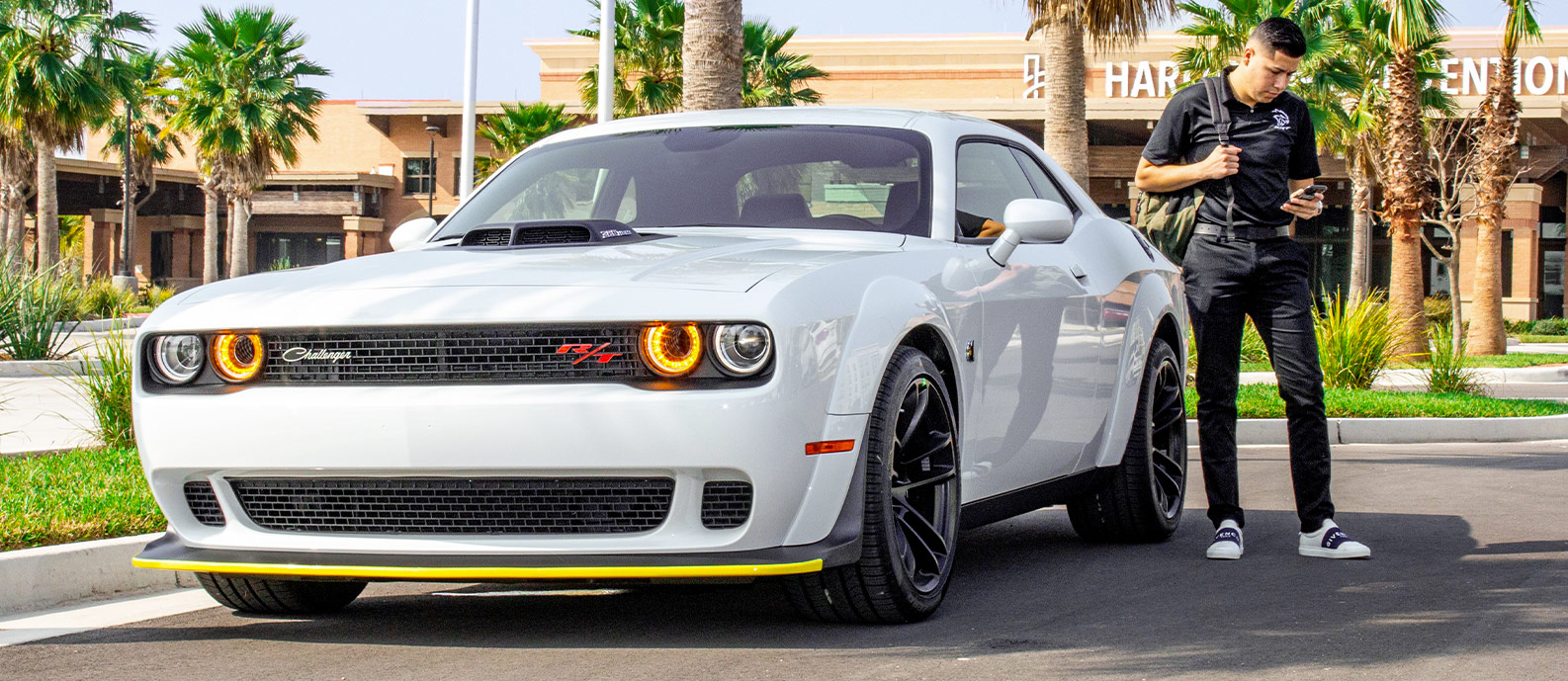 guy with a backpack getting out of his new dodge challenger