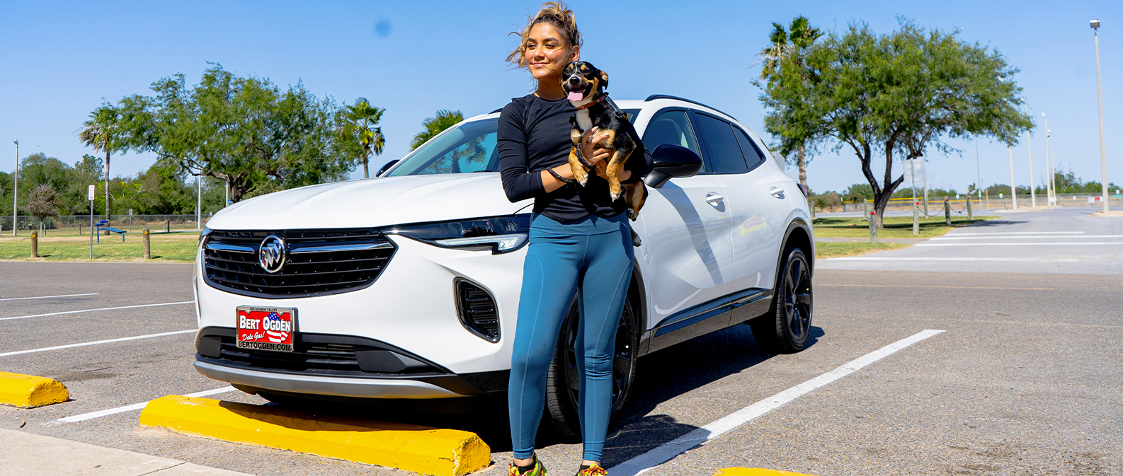 happy woman holding a dog in front of her new buick
